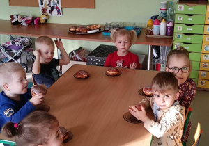 Kilkoro dzieci z grupy "Motylków" przy stoliku podczas podwieczorku - pączka z marmoladą.
