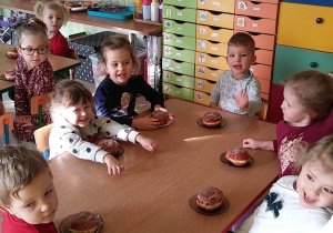 Kilkoro dzieci z grupy "Motylków" przy stoliku podczas podwieczorku - pączka z marmoladą.