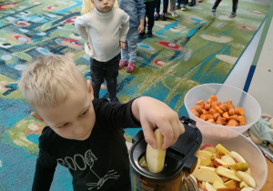 Dzieci z grupy "Motylków" podczas przygotowania naturalnego soku jabłkowo-marchewkowego z dodatkiem cytryny za pomocą sokowirówki.