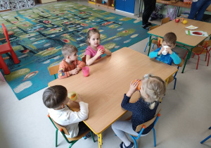 Degustacja naturalnego soku w grupie "Motylków". Dzieci siedzą przy stoliku.