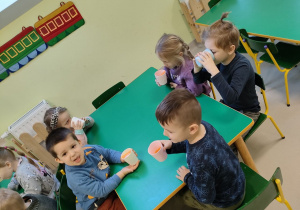 Kilkoro dzieci z grupy "Biedronek" przy stoliku w trakcie degustacji pysznego, naturalnego soku.