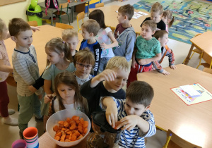Dzieci z grupy "Skrzatów" ustawione w "pociąg" wspólnie przygotowują naturalny sok jabłkowo-marchewkowy z dodatkiem cytryny przy wykorzystaniu sokowirówki.