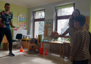 Dzieci ze starszych grup podczas zabawy ruchowej przy użyciu piłki i obręczy.