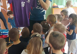 Pan Kamil prezentuje dzieciom koszulkę treningową.