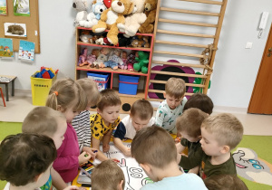 Dzieci wspólnie kolorują wiosenną kolorowankę na dużym formacie.