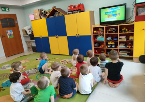 Dzieci oglądają film edukacyjny o wiośnie podczas oczekiwania na gimnastykę.