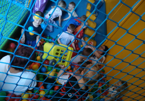 Zabawa kilku dzieci oraz cioci Ani i cioci Bożenki na zjeżdżalni i w basenie z piłkami w Sali Zabaw.
