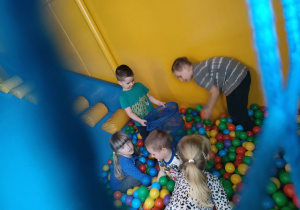 Kilkoro dzieci podczas zabawy w basenie z piłeczkami.