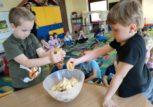 Dominik i Fabian ze Skrzatów dodają do sałatki owocowej miód i sok z cytryny.