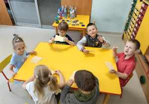 Kilkoro dzieci przy stole podczas degustacji wafelków z dodatkiem miodu.