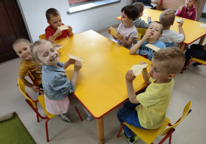 Kilkoro dzieci przy stole podczas degustacji wafelków z dodatkiem miodu.