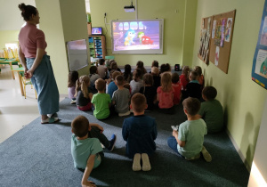 Dzieci w sali "Biedronek" oglądają film pt."W głowie się nie mieści" na tablicy multimedialnej.
