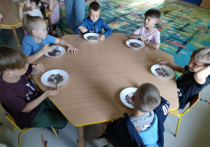 Kilkoro dzieci przy stole w trakcie śniadania-płatki czekoladowe z mlekiem.