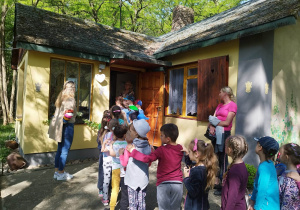 Dzieci oczekują na wejście do domku działkowego pisarki.