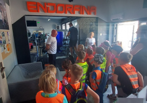 Państwo Karczewscy witają dzieci i zapraszają na sale siłowni. W tle na górze znajduje się napis ''Endorfina''.