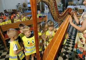 Dzieci z grupy Pszczółek grają na wielkiej harfie.