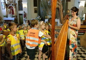 Dzieci z grupy Kaczuszek grają na wielkiej harfie.