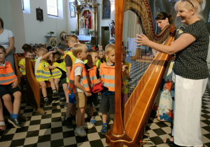 Dzieci z grupy Skrzatów grają na wielkiej harfie.