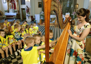 Dzieci z grupy Pszczółek grają na wielkiej harfie.