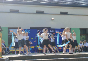 Grupa dziewczyn trzymając wstążki w jednej ręce podczas wykonywania układu tanecznego.
