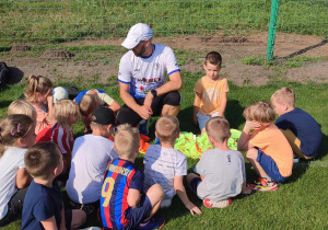 Dzieci z grupy "Biedronek" słuchają trenera piłki nożnej - p. Mateusza Maciejewskiego.