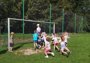 Dzieci z grupy "Skrzatów" w trakcie zabawy ruchowej na boisku sportowym.