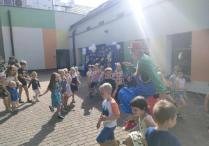 Dzieci w trakcie zabaw muzyczno-ruchowych prowadzonych przez wodzireja na tarasie przedszkolnym.