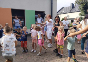 Wspólna zabawa dzieci, ich rodzin oraz personelu przedszkola na tarasie przedszkolnym.