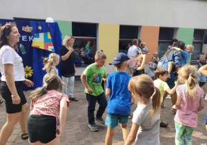 Wspólna zabawa dzieci, ich rodzin oraz personelu przedszkola na tarasie przedszkolnym.