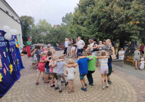 Wspólne tańce dzieci, ich rodzin oraz personelu przedszkola na tarasie.