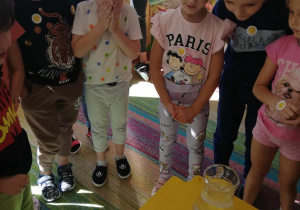Dzieci z grupy "Skrzatów" obserwują, co się dzieje z kolorowymi cukierkami w ciepłej wodzie.