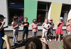 Dzieci z grupy "Skrzatów" puszczają bańki mydlane na tarasie przedszkolnym.