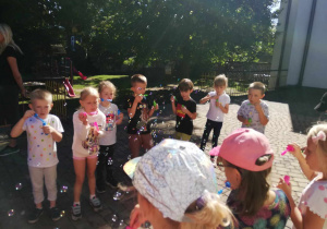 Dzieci z grupy "Skrzatów" puszczają bańki mydlane na tarasie przedszkolnym.
