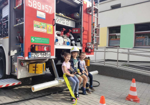 Troje dzieci ze "Skrzatów" podczas pamiątkowego zdjęcia na tle wozu strażackiego.