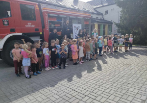 Dzieci z grup starszych wraz ze Strażakami z OSP w Ozorkowie na tle wozu strażackiego.