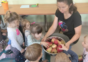 Ciocia Iwonka prezentuje dzieciom jabłka.