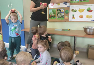 Nauczycielka pokazuje dzieciom jabłko i jabłoń.