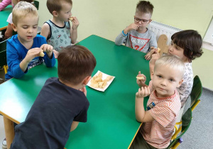 Kilkoro dzieci z "Pszczółek" przy stoliku chętnie zjada jabłka.