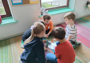 Kilkoro dzieci ze "Skrzatów" składa w całość i nakleja na kartkę ilustrację chomika.