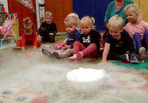 Doświadczenie chemiczne - "dywan" z wykorzystaniem ciepłej wody i dużej ilości kostek suchego lodu wśród dzieci młodszych.