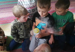 Chłopiec ze "Skrzatów" trzyma kubek z wodą oraz kostkami suchego lodu.