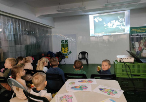 Dzieci z grupy "Pszczółek" oglądają film edukacyjny o zdrowym odżywianiu, jednocześnie zjadając pyszne jabłka, gruszki.