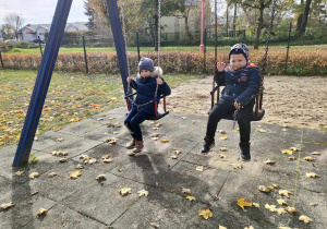 Aktywny odpoczynek na placu zabaw w parku miejskim - Kajtek i Antek na huśtawkach.