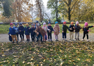 Dzieci w parku miejskim gotowe do startu, by wziąć udział w zabawie "Kto pierwszy?".