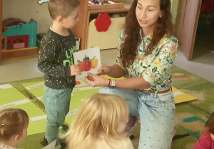 Pani Lidia Antczak wraz z Alankiem prezentują dzieciom ilustrację papryk.