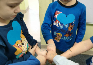 Jasnoniebieskie, brokatowe serca na dłoniach dzieci.
