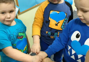 Jasnoniebieskie, brokatowe serca na dłoniach dzieci.