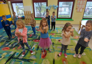 Dzieci z grupy "Biedronek" podczas zabawy ruchowej, polegającej na naśladowaniu ruchem/gestem wypowiedzianego przez nauczycielkę prawa dziecka.