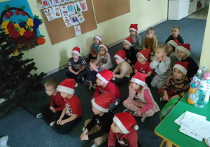 Dzieci z grupy Pszczółek oglądają film edukacyjny o Mikołaju na tablicy multimedialnej.