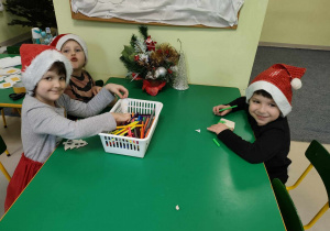 Kilkoro dzieci z grupy Pszczółek ozdabia mazakami zawieszki na klasową choinkę.